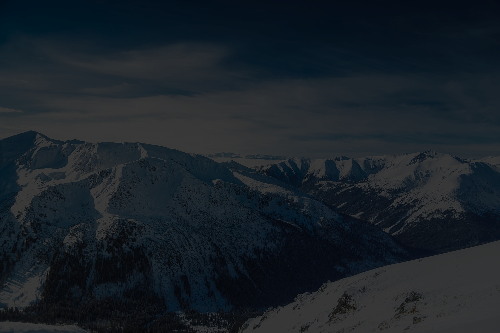 Snowy mountain ridge beneath a dark sky